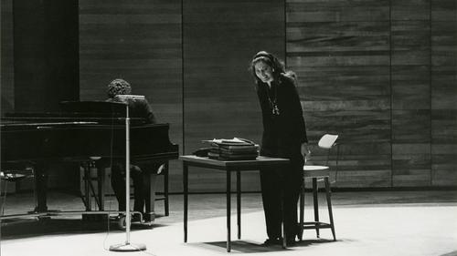 Black and white archival photo of Maria Callas on stage smiling toward the audience during a master class at Juilliard